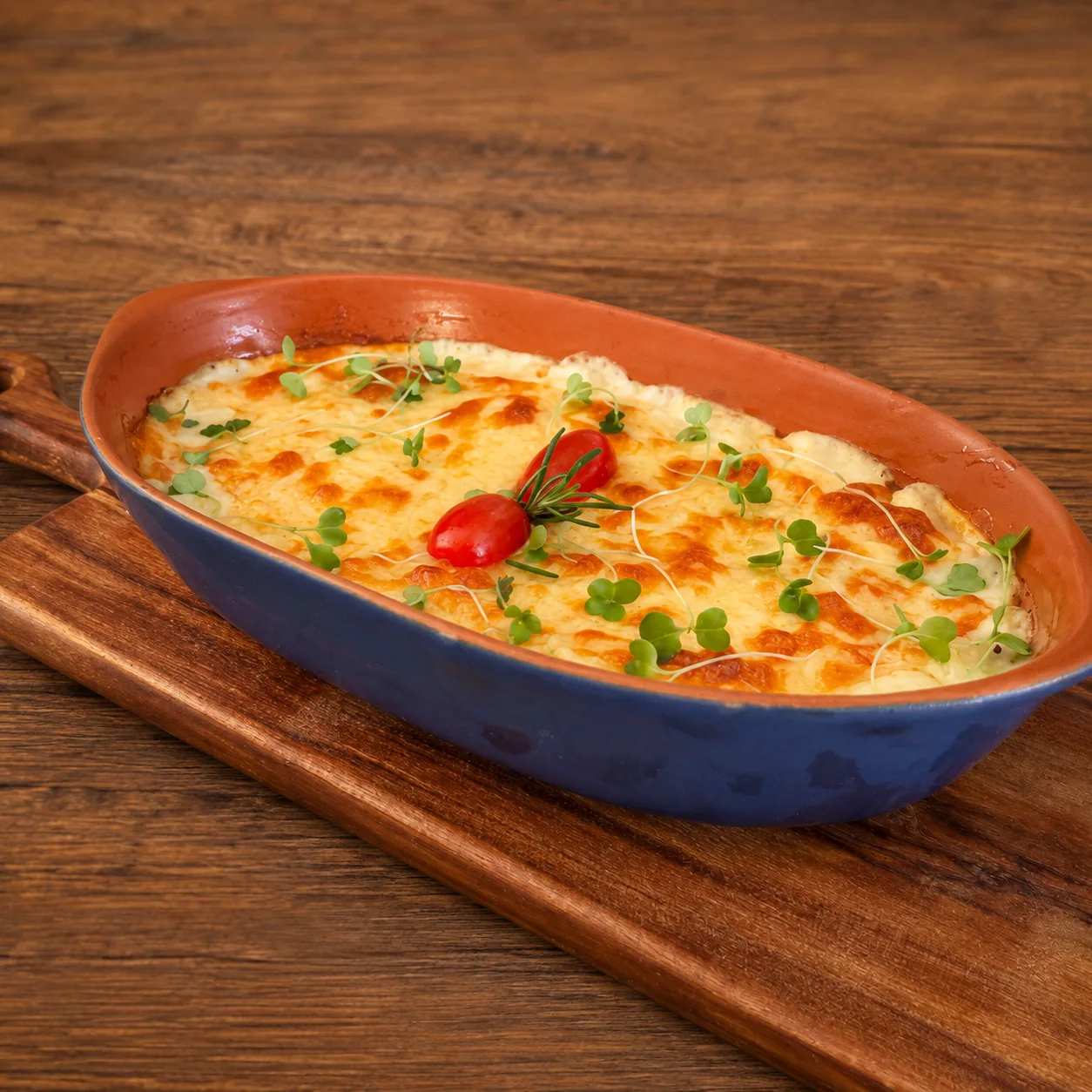 Bacalhau em natas gratinado servido em prato preto